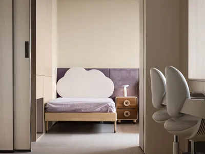 A minimalist bedroom featuring a cloud-shaped headboard, purple upholstered wall, and wooden nightstand.