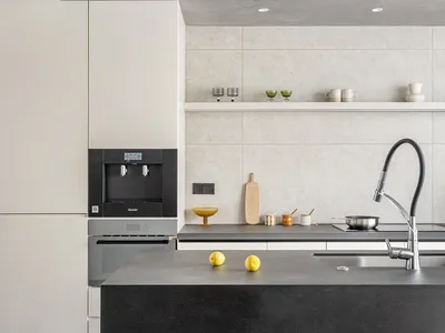 A minimalist residential kitchen with a sleek, industrial concrete countertop, featuring stainless steel appliances and a mod