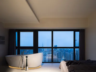 Modern bathroom featuring a large free-standing bathtub with a cityscape view through the floor-to-ceiling windows.