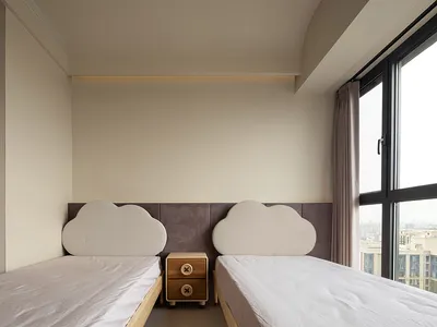 A minimalist bedroom with a cloud-shaped upholstered headboard, white bedding, and a small wooden nightstand between two sing