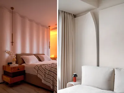A minimalist bedroom with a white bed and a white headboard, featuring a wooden nightstand and a hanging light fixture.