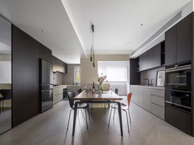 Modern kitchen with wooden countertops and table, featuring stainless steel appliances and a large window.