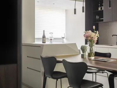 Modern kitchen with wooden table, black chairs, and a vase of flowers.