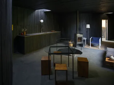 極簡風格的廚房，擁有混凝土地板、牆面與餐桌，以及木製吧台椅。