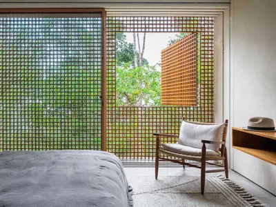 A modern bedroom with glass walls and a single white armchair.