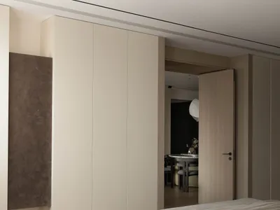 A modern bedroom featuring a bed with a neutral-toned blanket and a large closet in the same color palette.