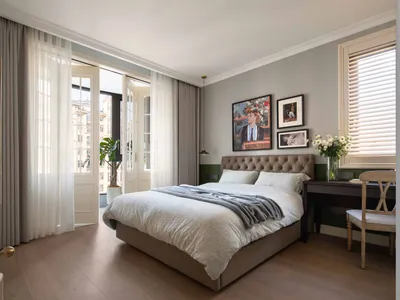 A minimalist bedroom featuring a comfortable bed, elegant furniture, and artistic wall decor, bathed in soft, natural light.