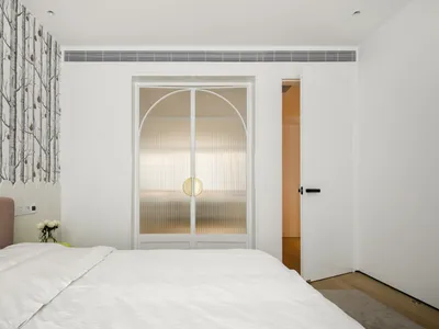 A serene minimalist bedroom with a white ceiling and a bed with a white comforter.