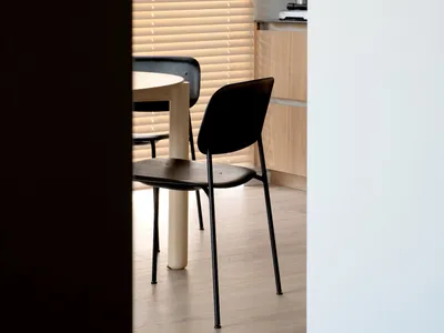 Minimalist kitchen with black chairs and wooden table, blinds closed.
