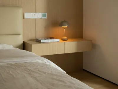 A minimalist bedroom with a wooden headboard and textured bedding.