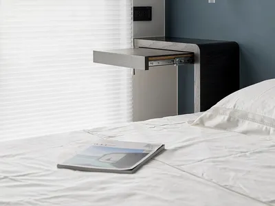 A minimalist bedroom featuring a wooden desk, blinds, and a comfortable bed with white bedding.