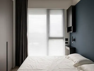 A modern bedroom with a bed, windows, and grey curtains.