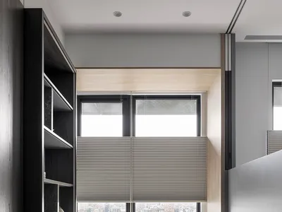 A modern home office featuring a wooden desk with a view of the cityscape outside the window.