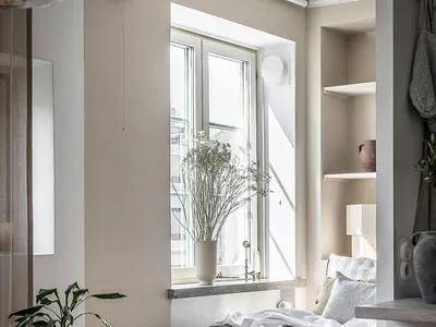 A minimalist bedroom with a wooden bed and window with white curtains.