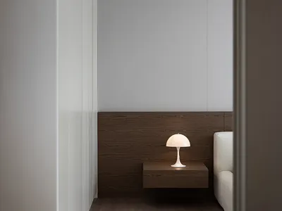 A minimalist bedroom featuring a wooden floor, a modern table lamp, and a white sofa.