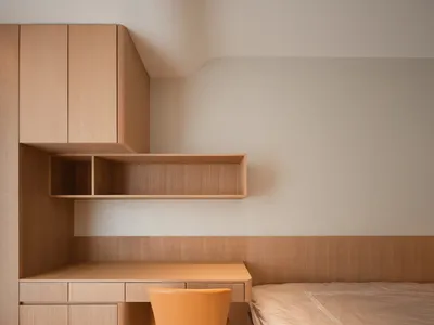 A modern minimalist bedroom featuring wooden furniture and surfaces.