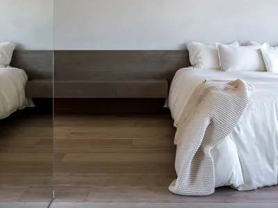 A minimalist bedroom with a wooden bed frame and fabric bedding.