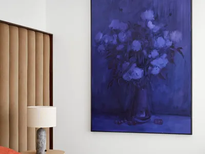 Bedroom featuring a modern design with a neutral color palette, upholstered headboard, and contemporary artwork.