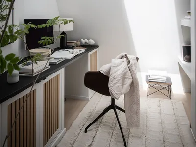 A modern home office featuring white walls and wooden elements.