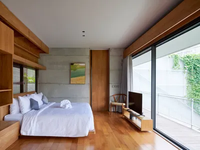 Modern bedroom with concrete accent wall and wooden flooring.