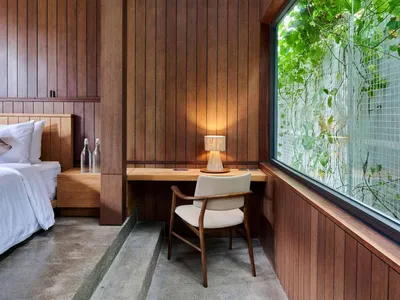 A minimalist bedroom with wooden walls and a desk area.