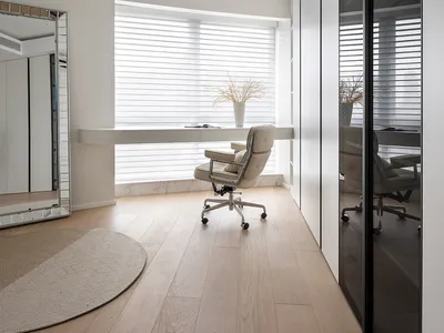A modern minimalist home office featuring a white marble desk and chair, with sleek white furniture and natural light streami