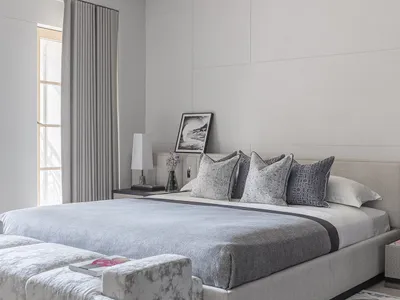 Modern minimalistic bedroom featuring upholstered furniture, neutral color palette, and abstract artwork.