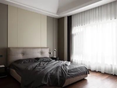 A modern bedroom featuring a brown upholstered bed with grey bedding and curtains, set against a muted color palette with a l