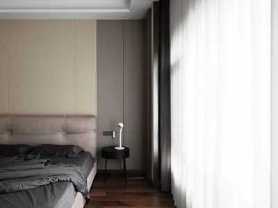 A modern bedroom with neutral-toned walls and furniture, featuring a bed with a dark gray duvet and pillows, a side table wit