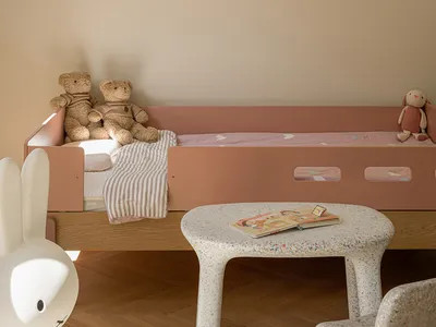 A minimalist child's bedroom featuring a wooden bunk bed with fabric bedding and stuffed animals.