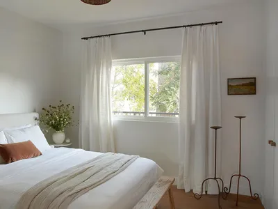 A minimalist bedroom with white curtains and a bed