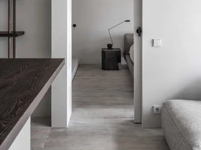 A minimalist bedroom with concrete walls and floors, featuring dark wood furniture and a simple, sleek design.