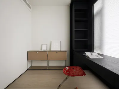 A minimalist home office featuring modern materials and a window seat with a red chair.