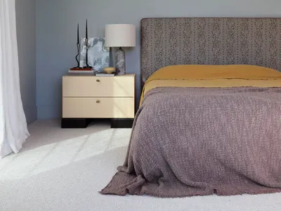 Minimalist styled bedroom featuring a headboard upholstered in fabric, accompanied by a wooden bedside table and a lamp.
