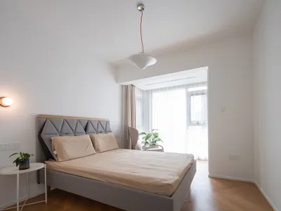 Minimalist bedroom with fabric bed and wooden floor.