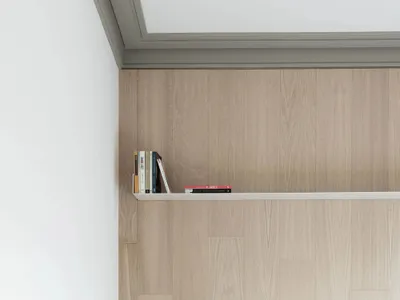 A minimalist bedroom featuring wooden furniture, white bedding, and a mounted clock.
