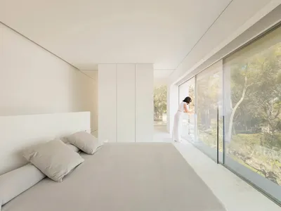 A modern bedroom featuring glass walls and a concrete floor.