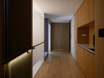 A minimalist residential interior featuring a wooden kitchen with a sleek, modern design.