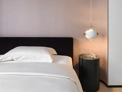 A modern bedroom featuring a fabric upholstered headboard and a white bed with white linens.