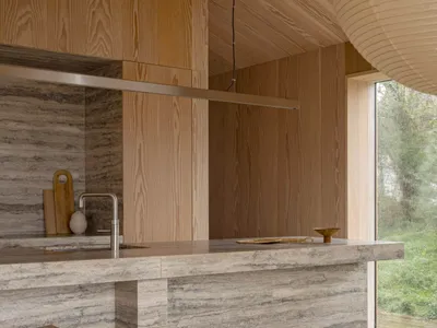 Modern kitchen with marble countertops and wooden stools.