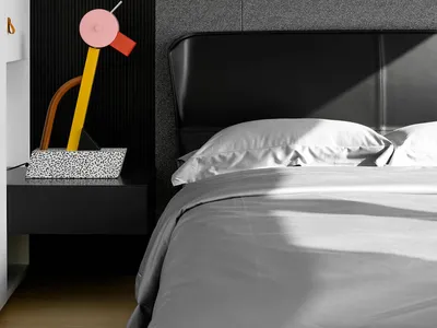 Modern minimalist bedroom featuring a black upholstered headboard and gray bedding.