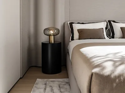 Modern minimalist bedroom featuring a bed with taupe fabric bedding and a side table with a decorative lamp.