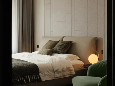 Modern bedroom featuring a fabric textured headboard, a green armchair, and ambient lighting.