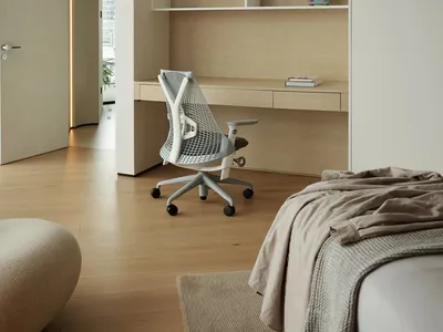 Modern minimalist master bedroom featuring a white desk with a mesh office chair, beige flooring, and light-colored wood cabi