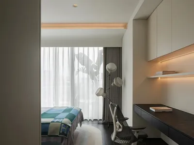Modern minimalist bedroom with neutral tones, featuring a bed covered in blue and green checkered bedding and a sleek, ergono