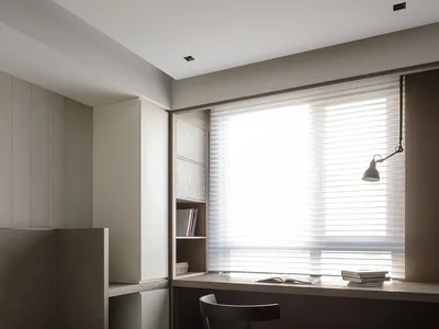 A modern minimalist bedroom with a window, wooden furniture, and white bedding.