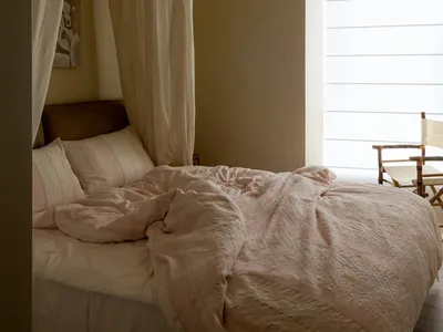 A minimalist bedroom with bluish fabric curtains and a comfortable-looking bed.