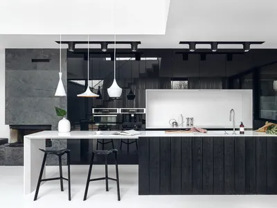 Modern minimalist kitchen with blackwood cabinets, white countertops, and white pendant lights hanging above the island.