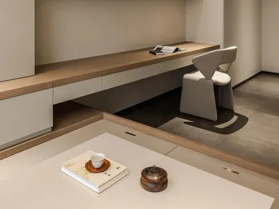 A minimalist home office featuring concrete and wooden surfaces with a sleek desk and modern chair