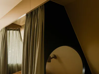 Minimalist bedroom with a bed, curtains, and a circular headboard.
